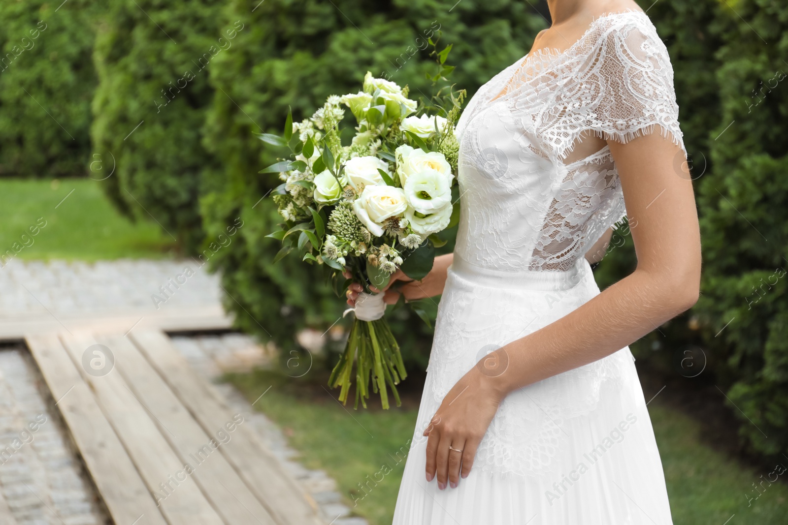 Photo of Bride in beautiful wedding dress with bouquet outdoors, closeup