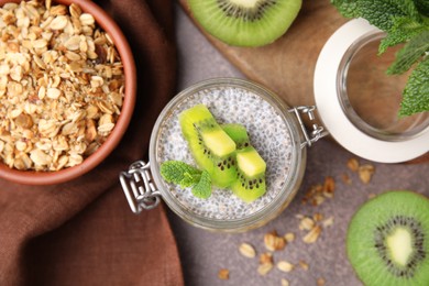 Photo of Delicious dessert with kiwi, fresh cut fruits and muesli on brown table, flat lay