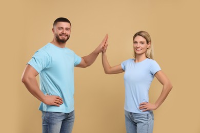 Photo of Happy couple giving high five on light brown background