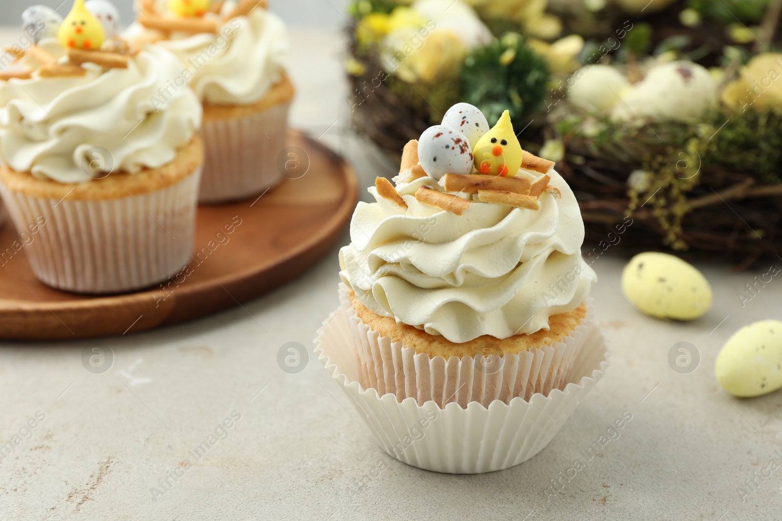 Photo of Tasty Easter cupcakes with vanilla cream and festive decor on gray table