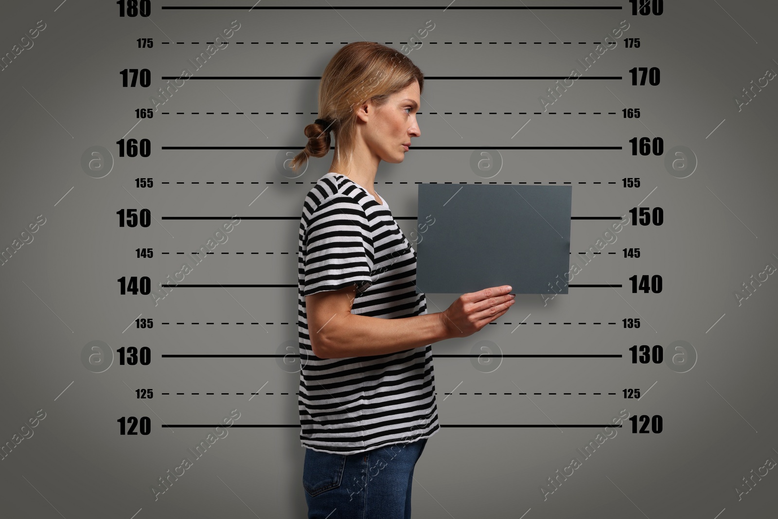 Image of Criminal mugshot. Arrested woman with blank card against height chart