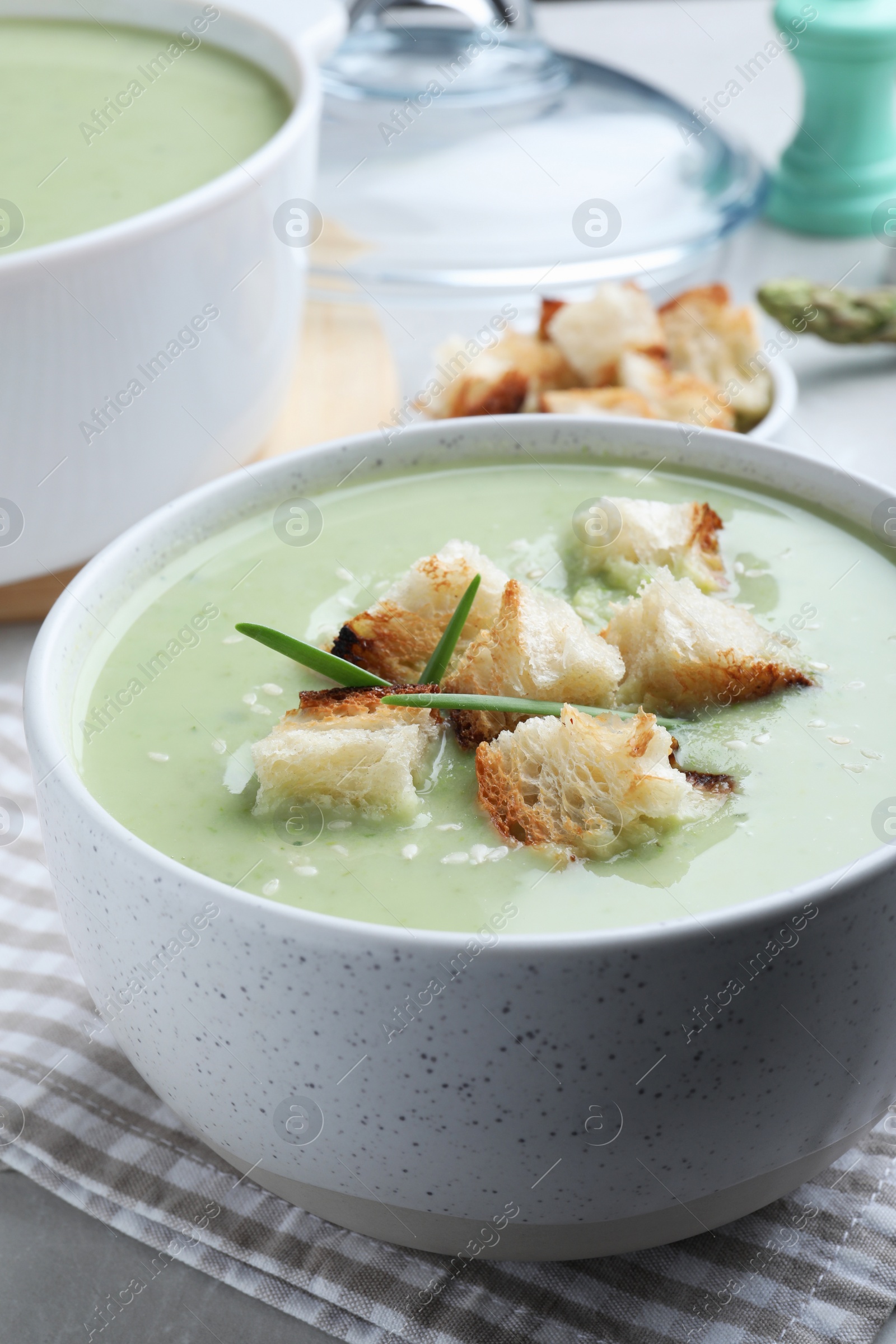 Photo of Bowl of delicious asparagus soup on table, closeup