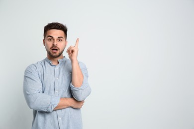 Photo of Emotional man on light background, space for text. Thinking about answer to question