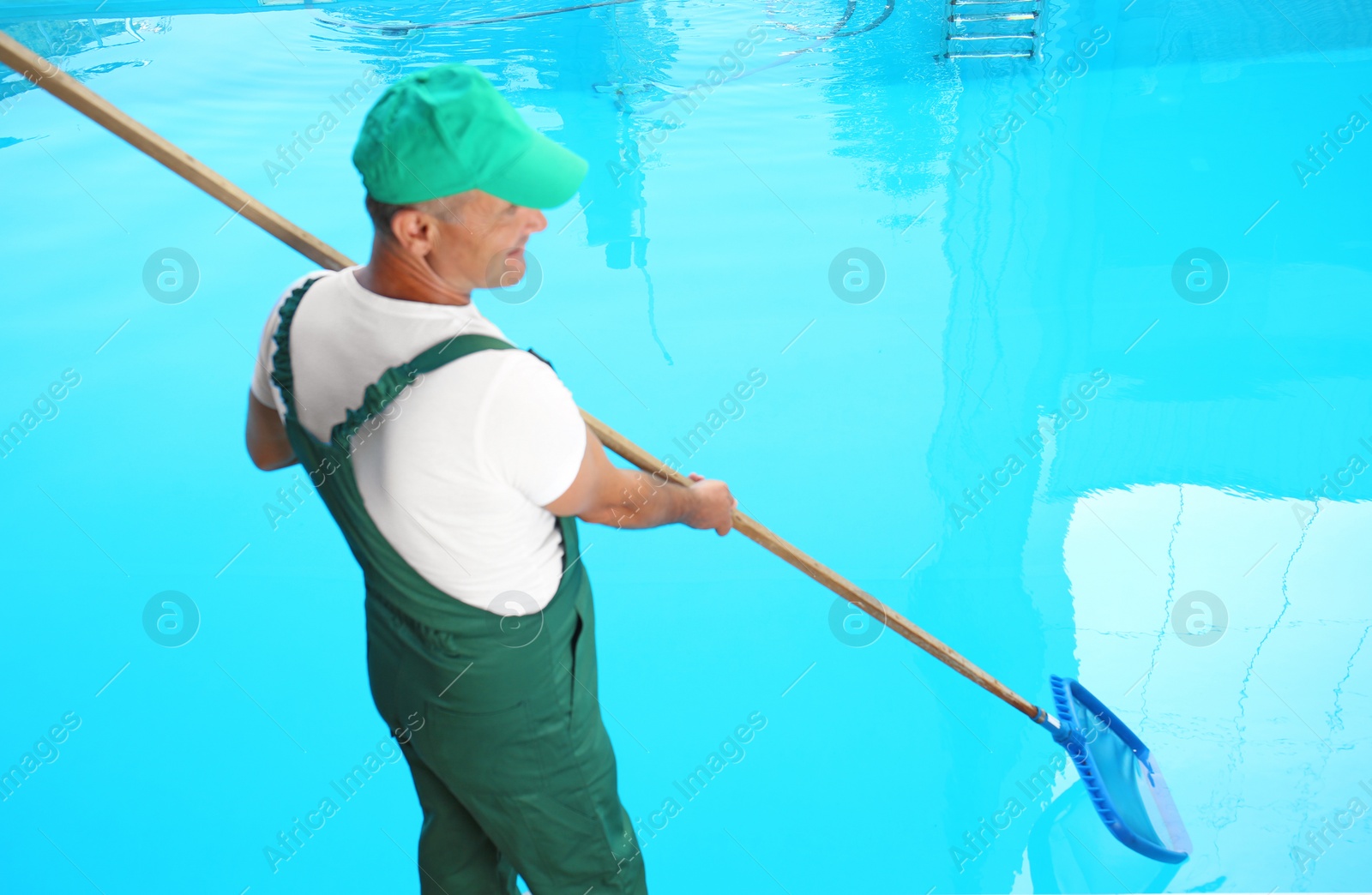 Photo of Male worker cleaning outdoor pool with scoop net