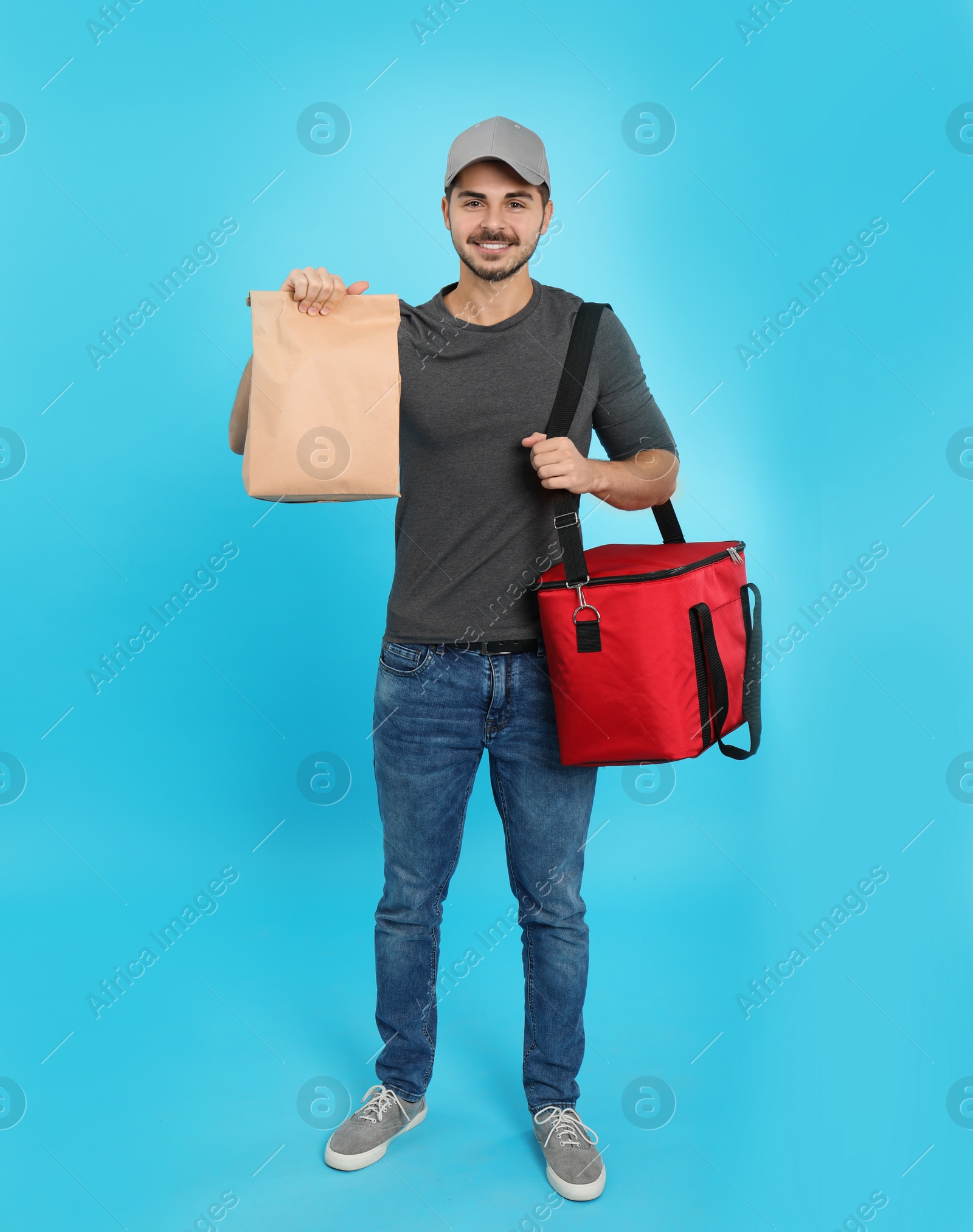 Photo of Young courier with thermo bag and paper package on color background. Food delivery service
