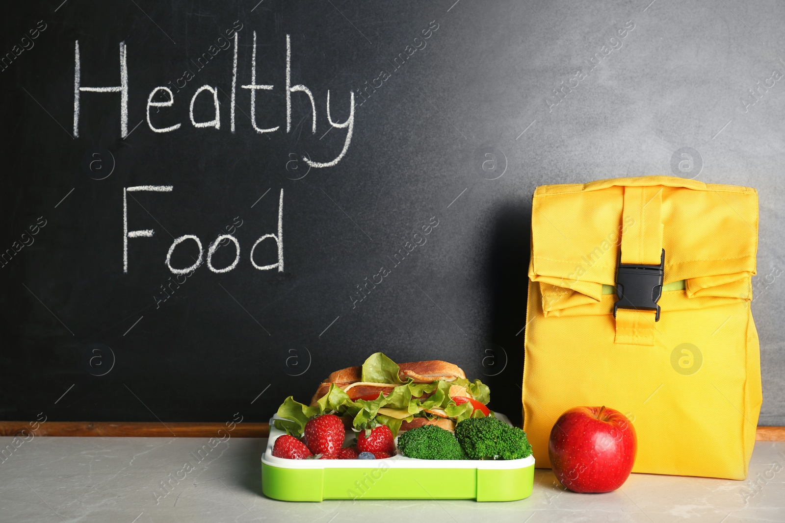 Photo of Lunch for schoolchild on table near blackboard with chalk written Healthy Food