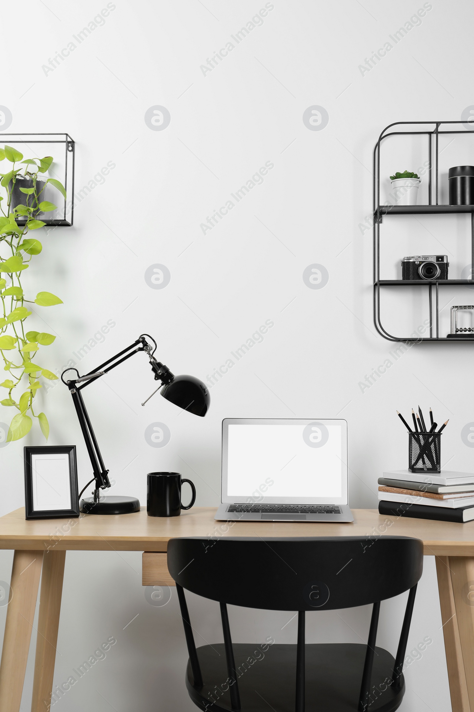 Photo of Cozy workspace with laptop, lamp and stationery on wooden desk at home