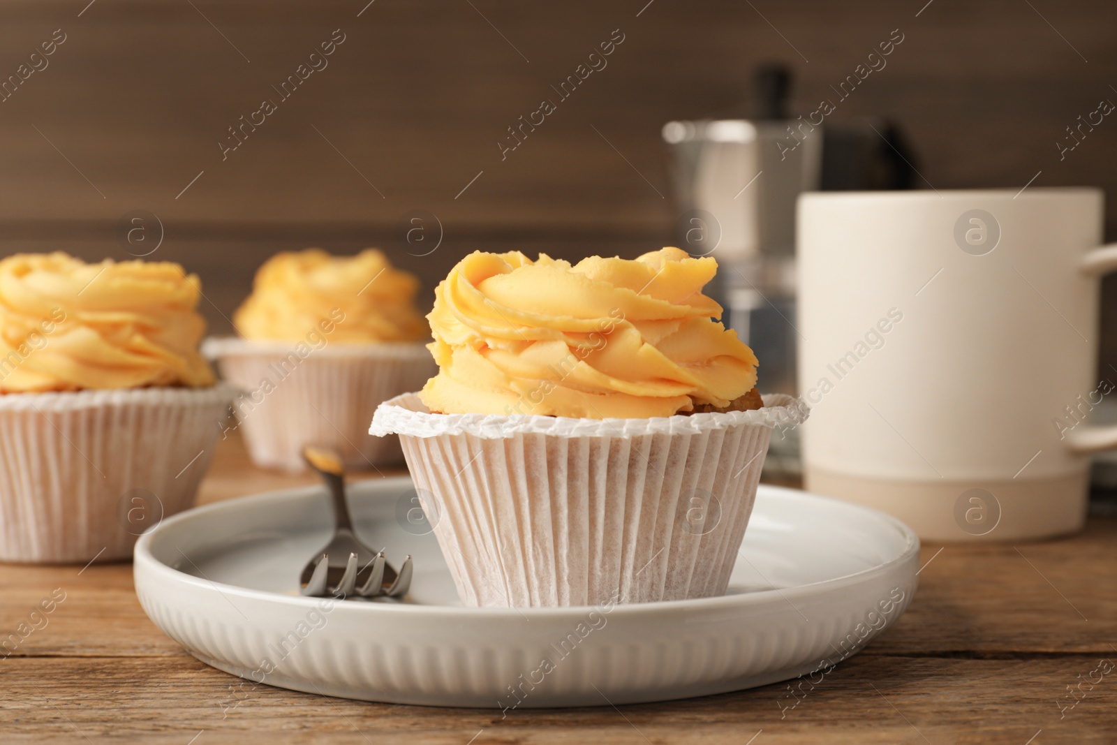 Photo of Tasty cupcakes with cream served on wooden table