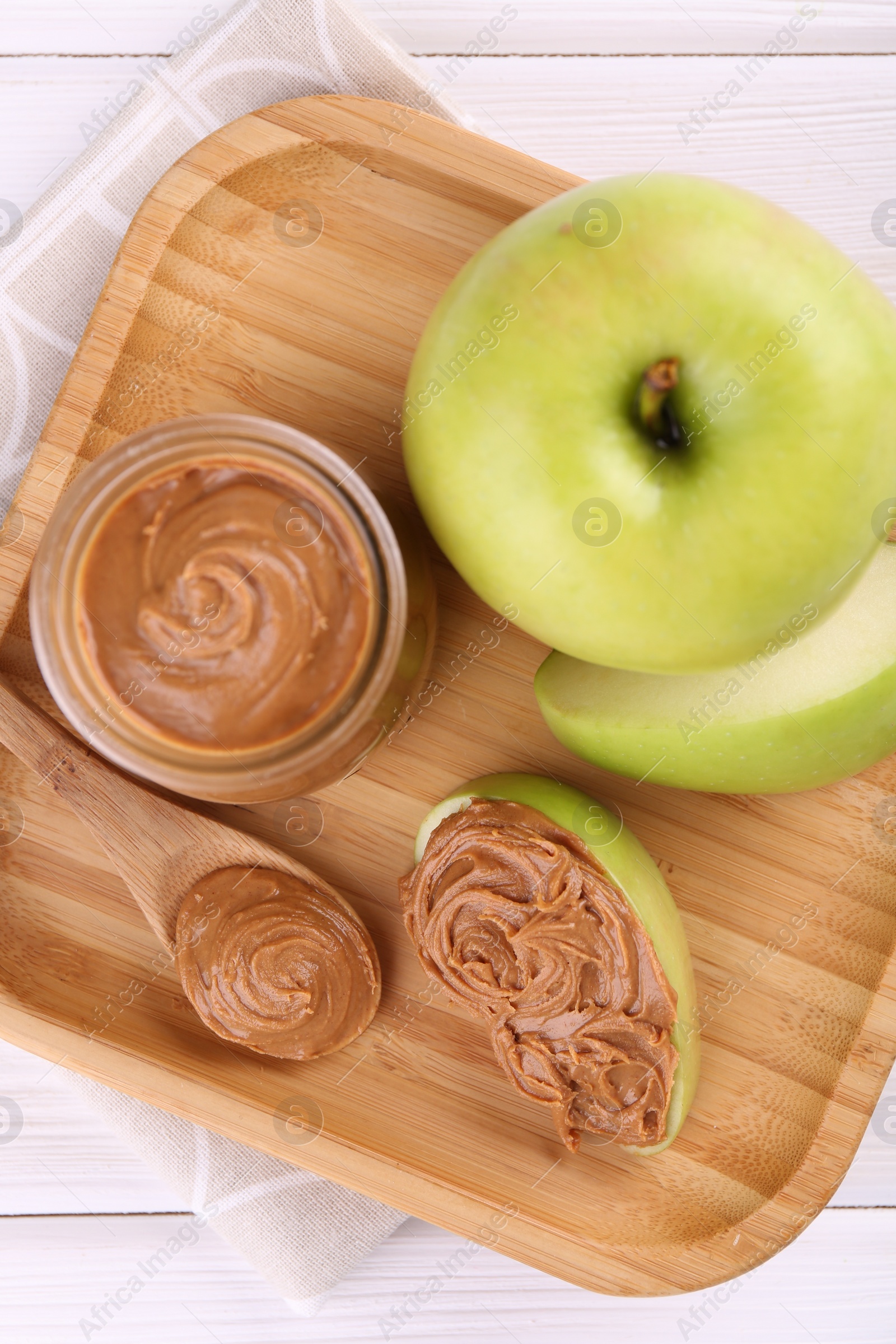 Photo of Fresh green apples with peanut butter on white wooden table, top view