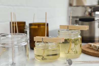 Glass jars with melted wax on white table. Handmade candles