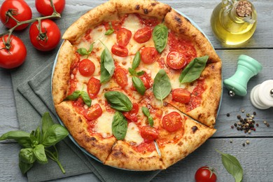 Photo of Delicious Margherita pizza and ingredients on gray wooden table, flat lay