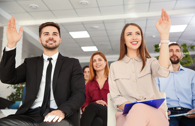 Photo of People raising hands to ask questions at business training indoors