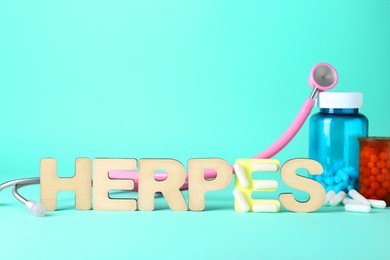 Photo of Word Herpes made of wooden letters, different pills and stethoscope on turquoise background