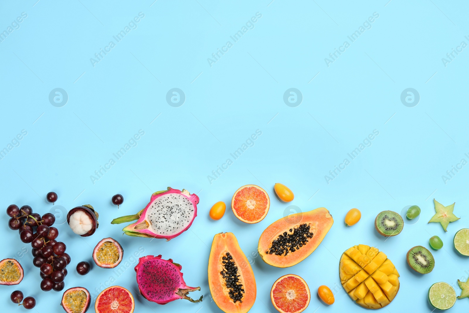 Photo of Many different delicious exotic fruits on light blue background, flat lay. Space for text