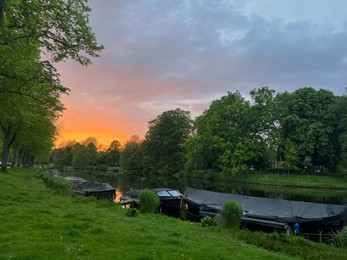 Scenic view of canal with moored boats at sunset