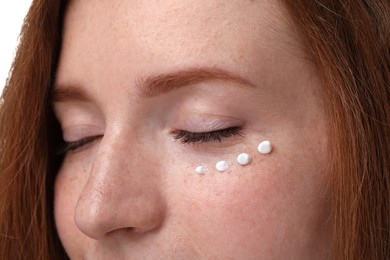 Photo of Beautiful woman with freckles and cream on her face, closeup