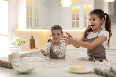 Photo of Cute little children cooking dough together in kitchen
