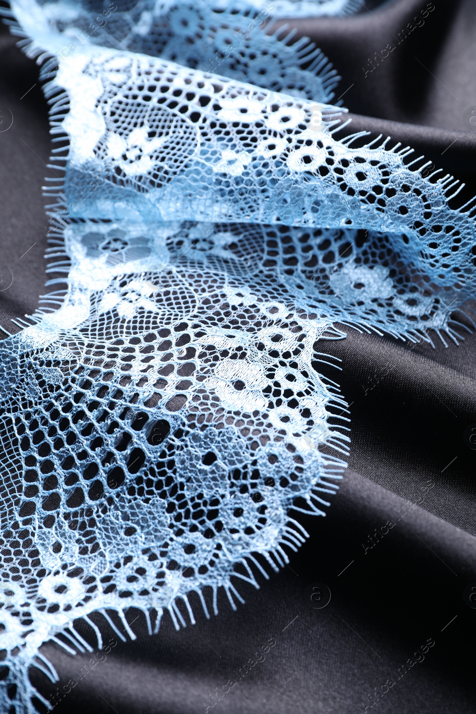 Photo of Beautiful light blue lace on black fabric, closeup