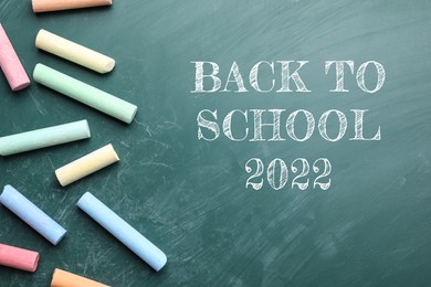 Back to school 2022. Pieces of color chalk on greenboard, flat lay