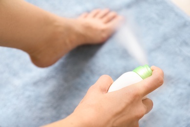 Photo of Young woman using foot deodorant at home, closeup