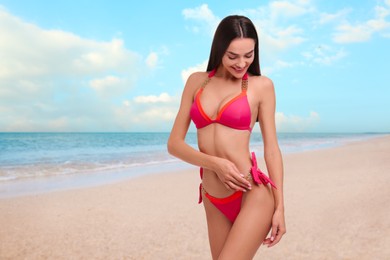 Image of Happy woman in stylish pink bikini on sandy beach near sea, space for text
