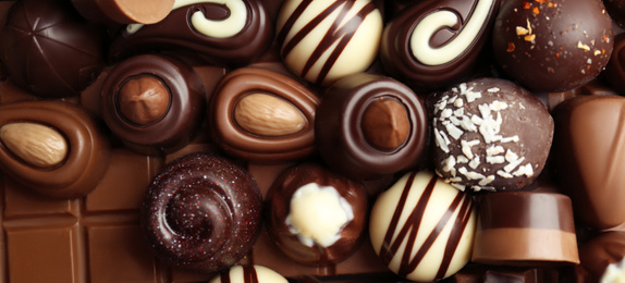 Image of Many different tasty chocolate candies as background, top view. Banner design 