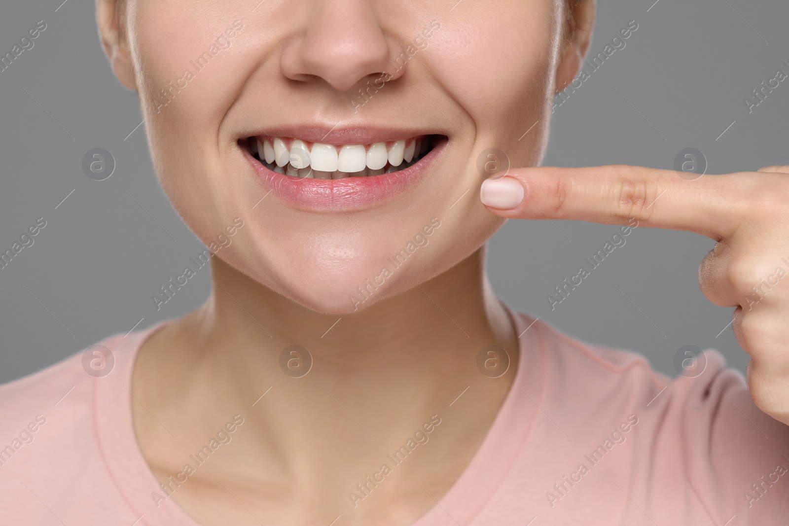 Photo of Woman showing healthy gums on gray background, closeup