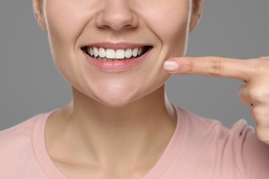 Photo of Woman showing healthy gums on gray background, closeup