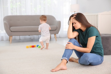 Photo of Young mother suffering from postnatal depression and little baby in room