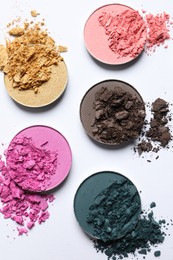 Photo of Different crushed eye shadows on white background, flat lay. Professional makeup product