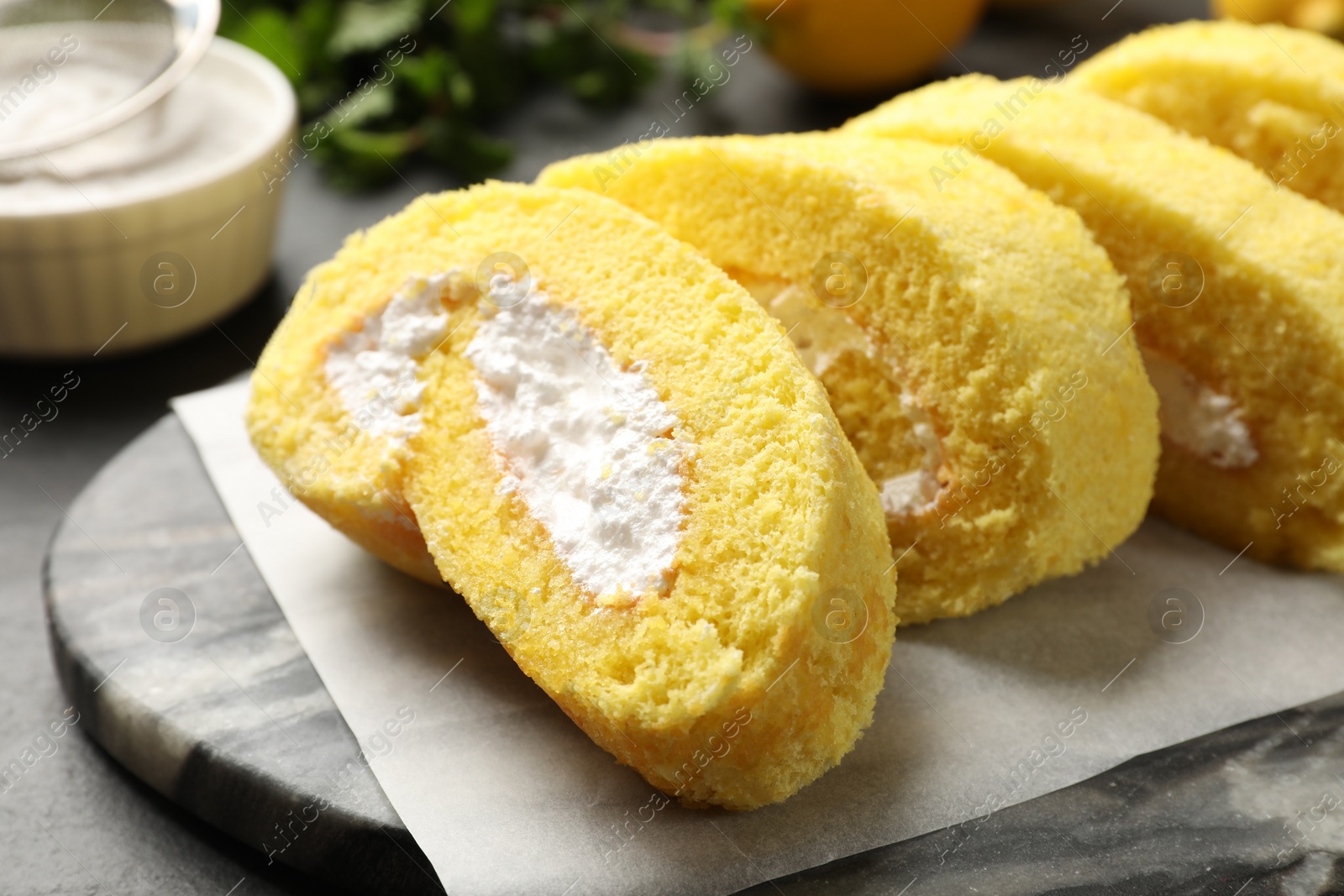 Photo of Delicious cake roll with cream filling on grey table, closeup