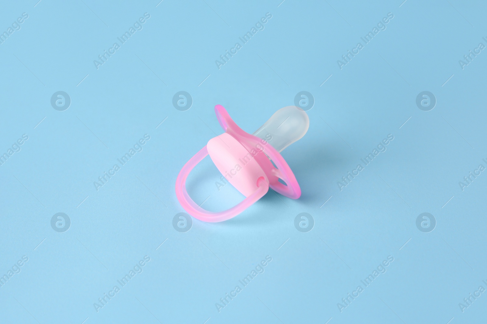 Photo of One new baby pacifier on light blue background