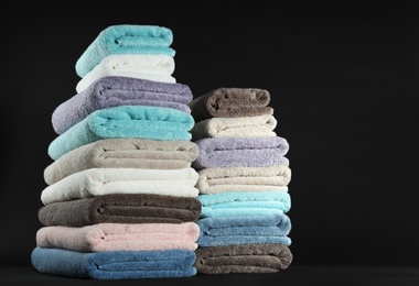 Photo of Different fresh soft terry towels on dark background