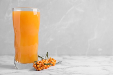 Delicious sea buckthorn juice and fresh berries on white marble table against grey background. Space for text