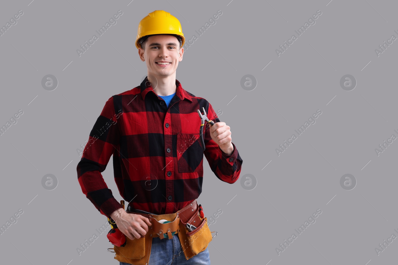 Photo of Young man holding pliers on grey background, space for text