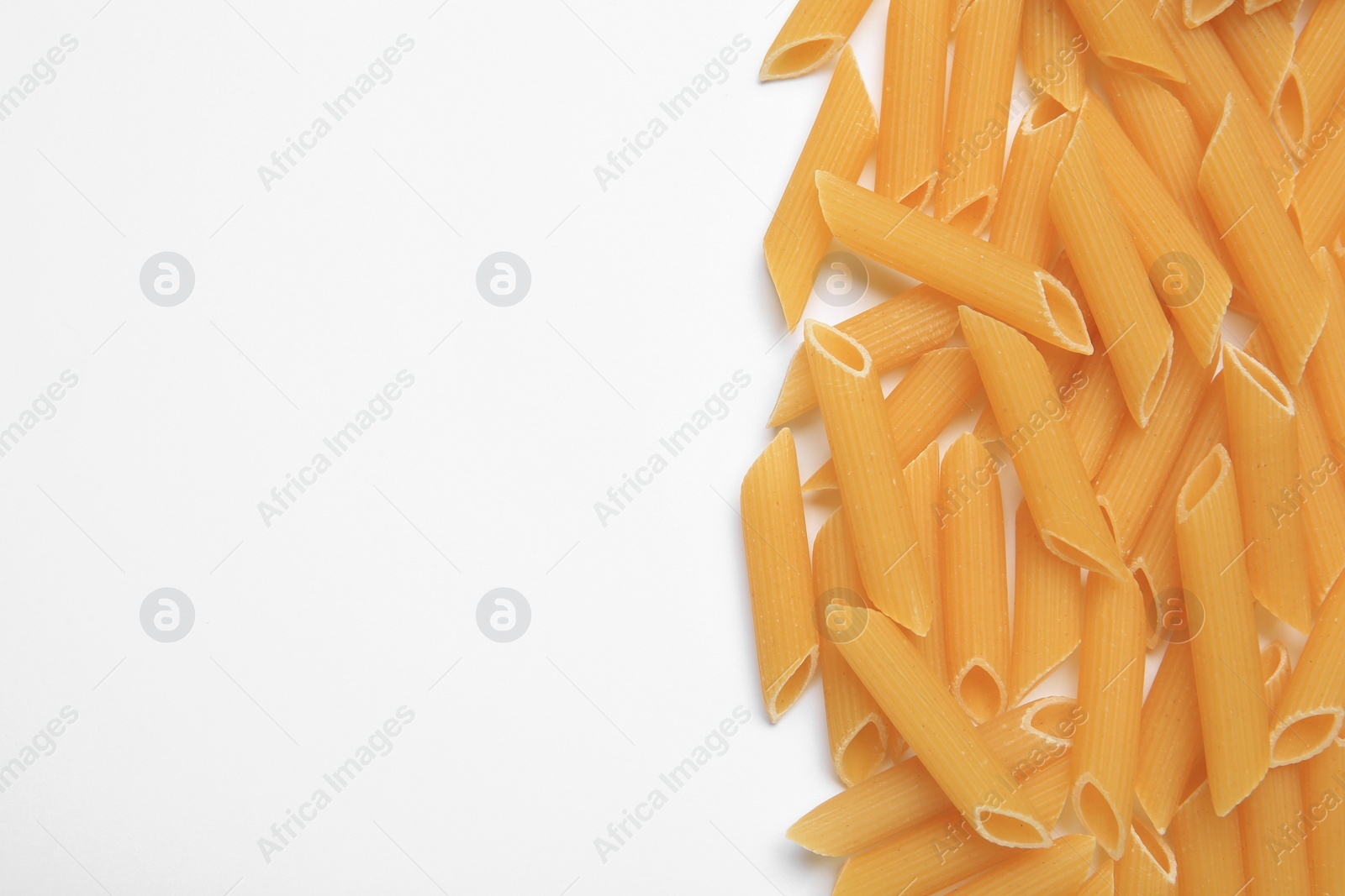 Photo of Raw penne pasta on white background, top view. Space for text