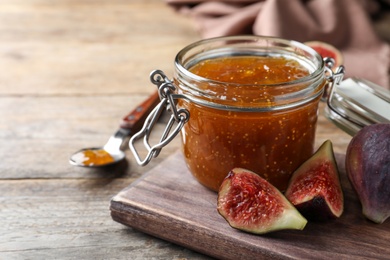 Photo of Homemade delicious fig jam and fresh fruits on wooden table, closeup. Space for text