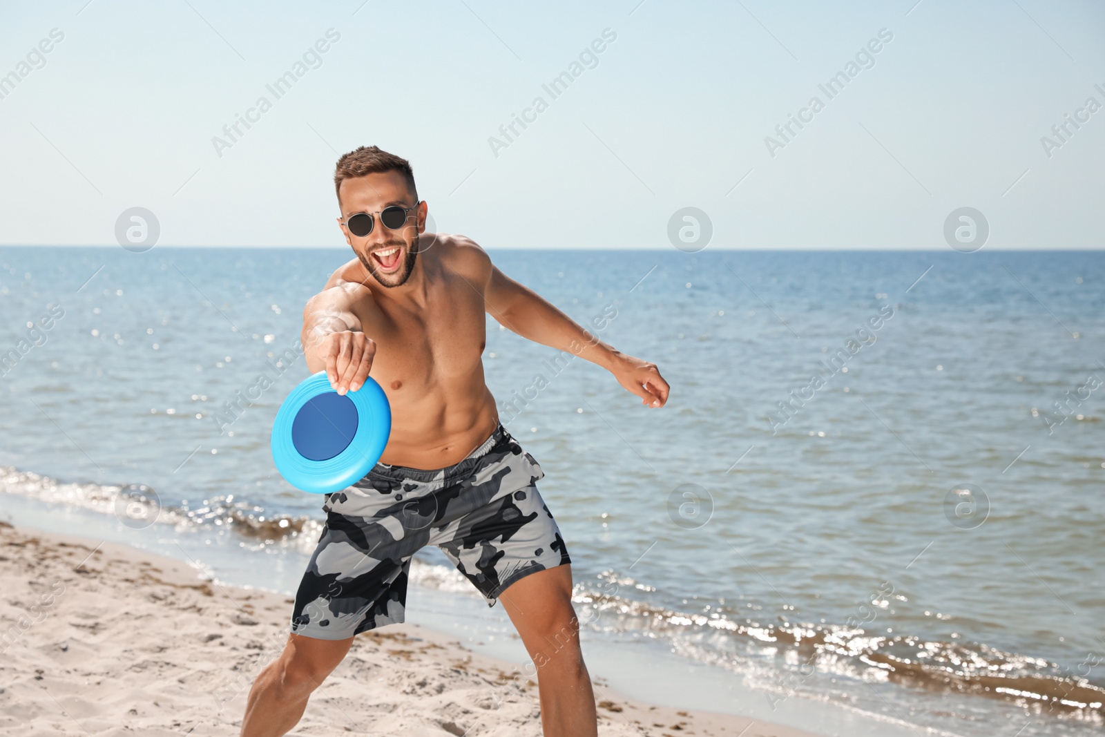 Photo of Happy man catching flying disk at beach on sunny day