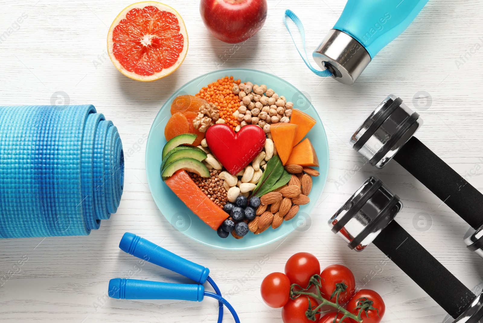 Photo of Plate with heart-healthy products and sports equipment on wooden background, flat lay