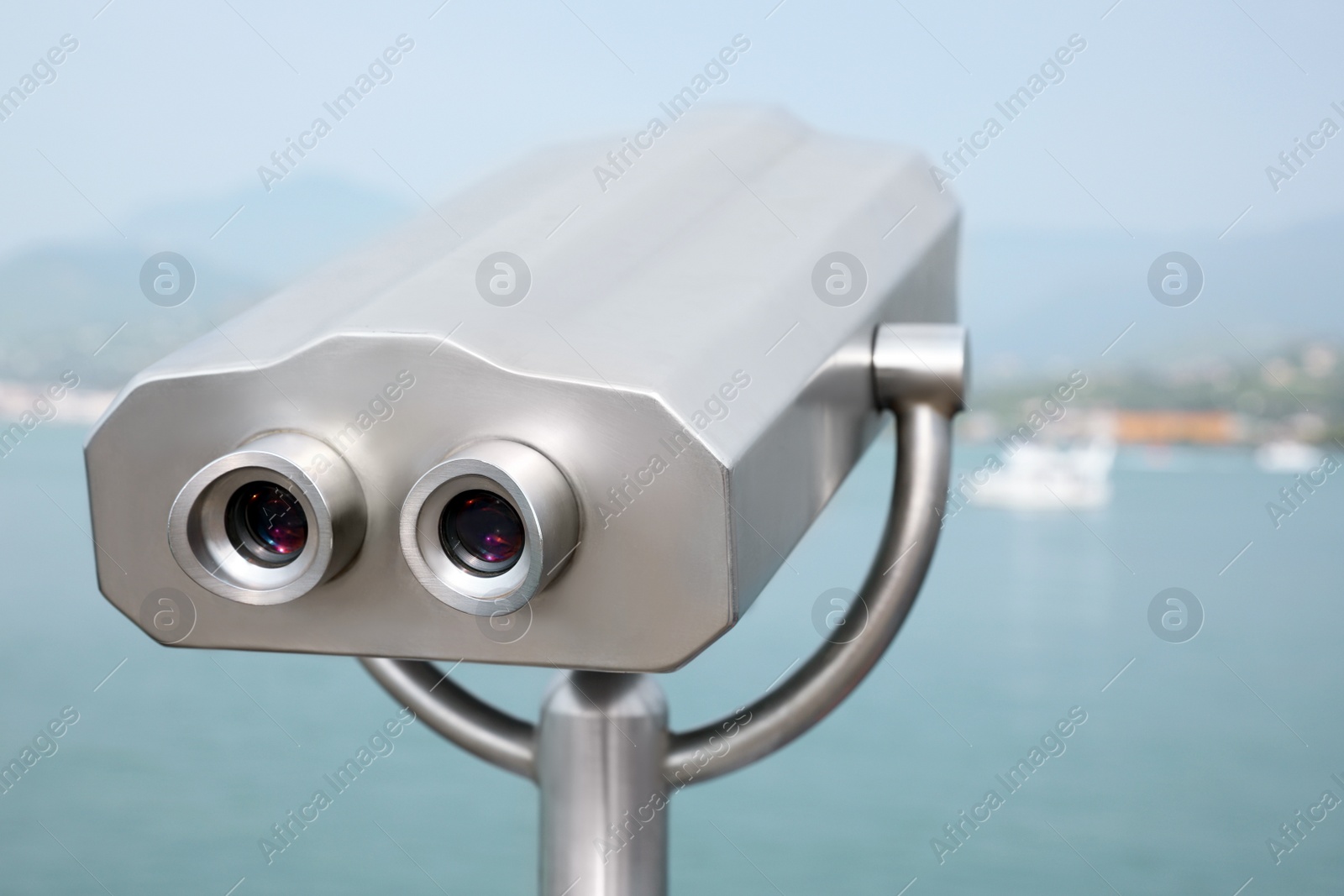 Photo of Metal tower viewer installed near sea. Mounted binoculars