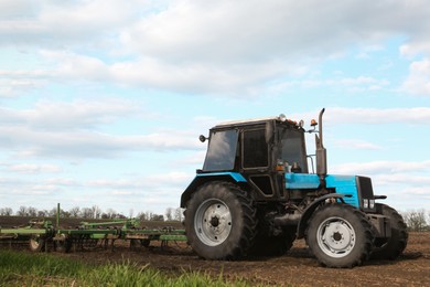 Photo of Tractor with planter cultivating field on sunny day. Agricultural industry