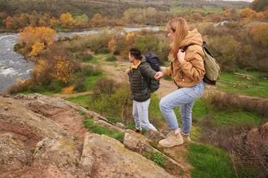 Photo of Couple of hikers with backpacks climbing down mountain