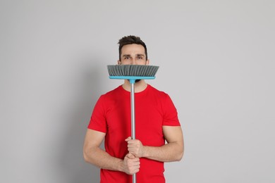 Photo of Handsome man with broom on grey background