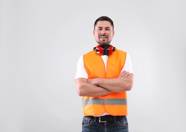 Photo of Male industrial engineer in uniform on light background. Safety equipment