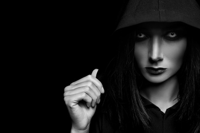 Photo of Mysterious witch with spooky eyes on dark background, space for text. Black and white effect