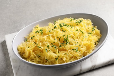 Bowl with cooked spaghetti squash on light background