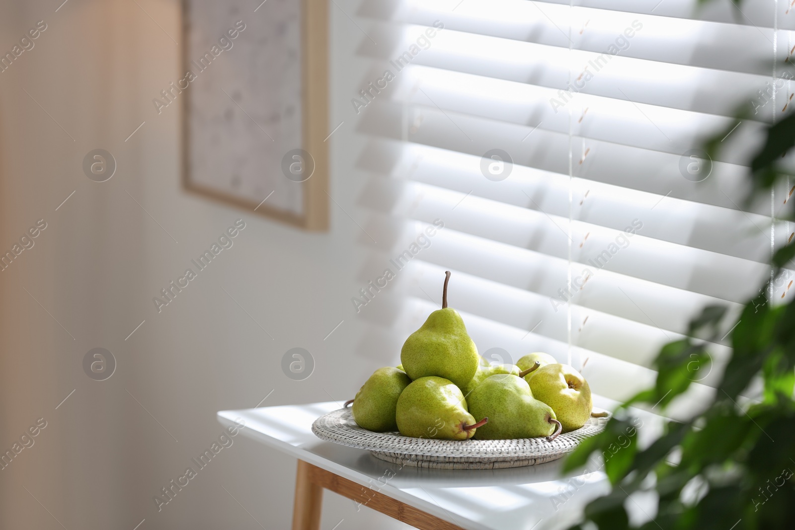 Photo of Fresh ripe pears on white table in room. Space for text