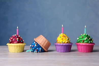 Photo of Dropped cupcake among good ones on white wooden table. Troubles happen