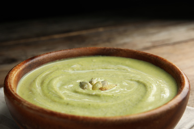 Photo of Bowl of delicious broccoli cream soup with pumpkin seeds, closeup