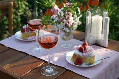 Photo of Vase with spring flowers, wine and cake on table served for romantic date in garden